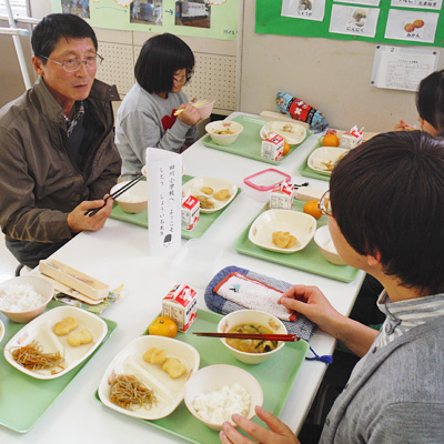 エコ農産物を使った給食を子供達と食べる志藤さんの画像