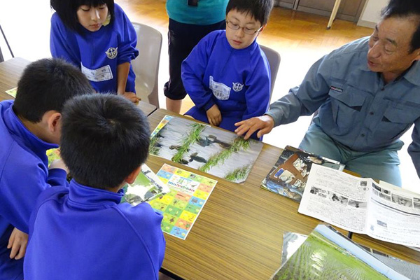 田んぼに生きる生き物の説明を受ける小学生たちの画像