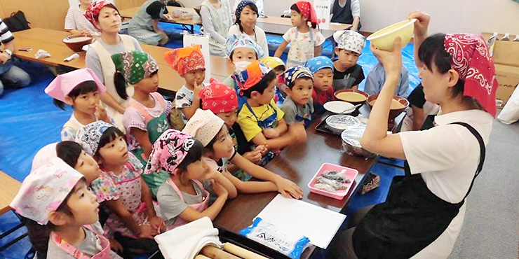 農薬不使用栽培のえだまめでじんだん餅をつくる幼稚園児と家族の画像